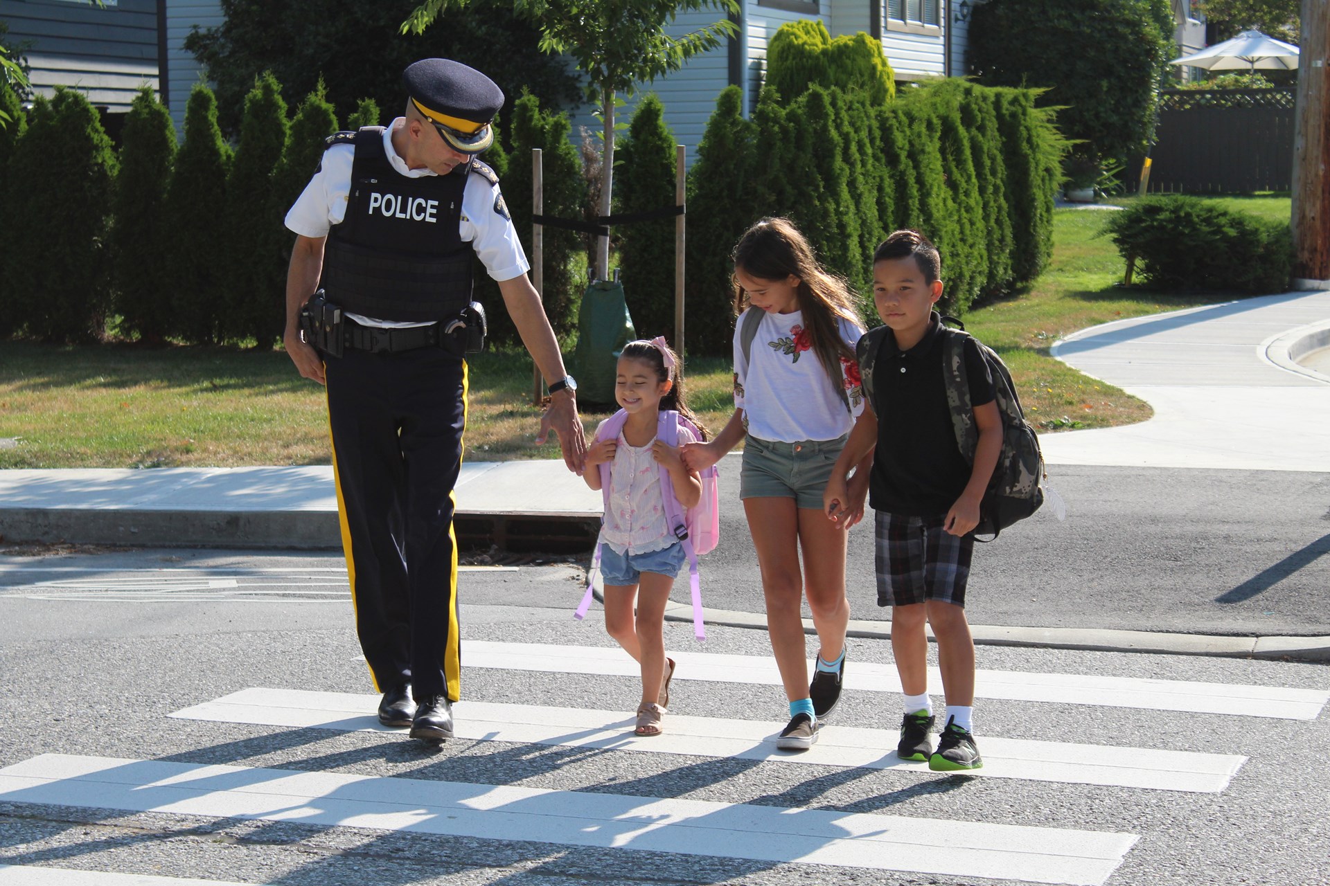 A police officer with three kids in a school zone assisting them.